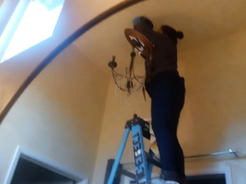 Electrician installing a chandelier in a Hobart residence